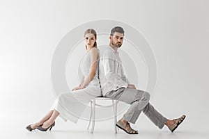 couple in linen clothes sitting back to back on chair