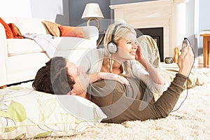 Couple Listening To MP3 Player Laying On Rug photo