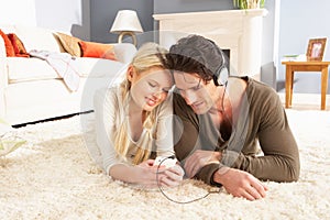 Couple Listening To MP3 Player Laying On Rug photo