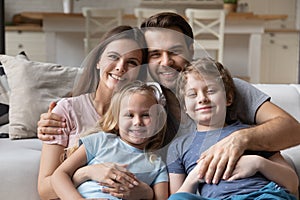 Couple and little children sitting on couch looking at camera