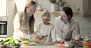 Couple and little daughter cook together in cozy kitchen