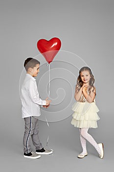 couple of little girl and boy with red heart balloons