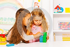 Couple little girls playing stacking wooden blocks