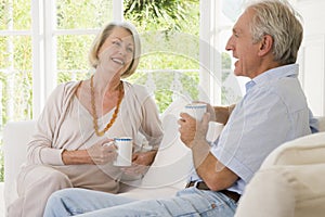 Couple in living room with coffee smiling