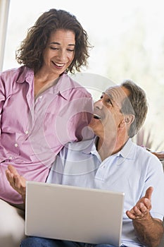 Couple in living room with laptop smiling