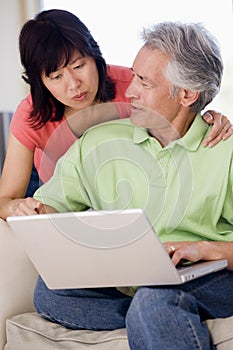 Couple in living room with laptop smiling