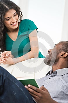 Couple in living room talking while sitting on sofa.