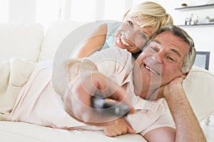 Couple in living room using remote control smiling