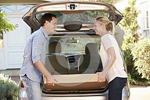 Couple Loading Large Package Into Back Of Car