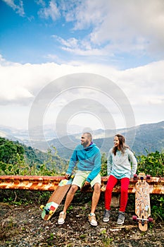 Couple with longboard and skateboard travel in tropcis of Asia