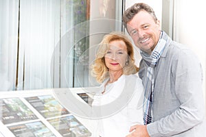 couple look at the window of a real estate agent to buy