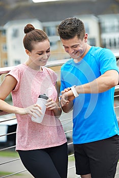 Couple Looking At Activity Tracker Whilst Exercising In City