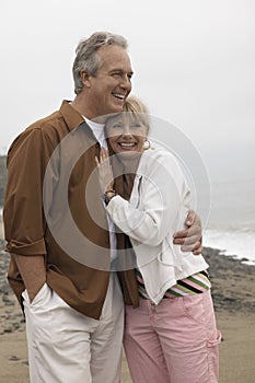 Couple Looking Away While Embracing Each Other On Beach