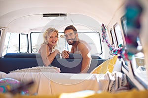 Couple looking at camera in camper van at beach