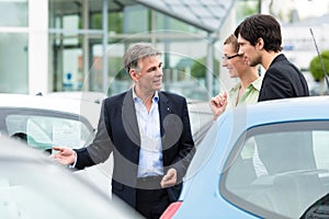 Couple looking at car on yard of dealer