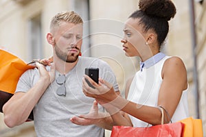 Couple looking at cellphone holding shopping bags