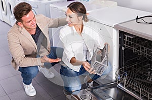 Couple looking at dishwashers in domestic appliances shop