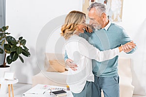 couple looking at each other while dancing in living room photo