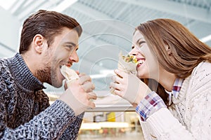 Couple looking at each other while eating fast food