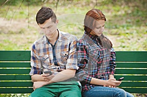A couple looking each in their mobile phone