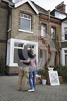 Couple Looking At House With Possessions Outside photo