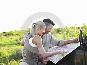 Couple Looking At Map On Jeep Bonnet At Landscape