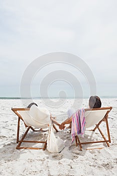 Couple looking ocean on their deck chairs