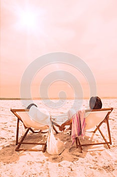 Couple looking ocean on their deck chairs