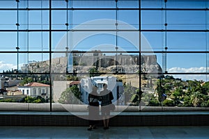 Couple looking out at the Acropolis throught huge glass window in the Acropolis Museum. Athens, Greece. photo
