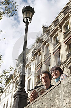 Couple Looking Over Bridge With Guidebook