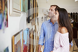 Couple Looking At Paintings In Art Gallery Together photo