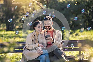 Couple looking reading SMS on smart phone in park