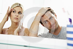 Couple Looking At Reflections In Mirror For Signs Of Ageing