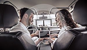 Couple is looking on tablet. The are looking options of brandnew car