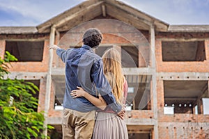 Couple looking at their new house under construction, planning future and dreaming. Young family dreaming about a new