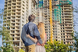 Couple looking at their new house under construction, planning future and dreaming. Young family dreaming about a new