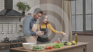 Couple looks at recipe on phone in kitchen for organic salad. Husband and wife cooking recipe food. Happy healthy together lifesty