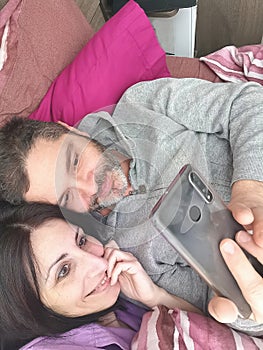 Couple looks at the smartphoneon the bed