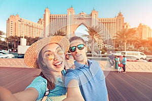 Couple in love arrived for their honeymoon in Dubai and takes a selfie in front of their hotel on the island of palm Jumeirah