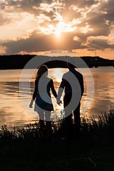 Couple in love back light silhouette at lake orange sunset