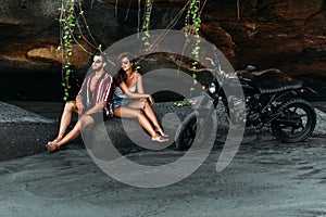 A couple in love on the beach meets the sunset. Beautiful couple on a bike. Lovers on the beach. A man and a woman on the beach.