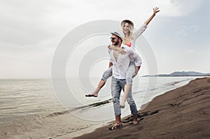 Couple in love on beach summer vacations. Joyful girl piggybacking on young boyfriend having fun