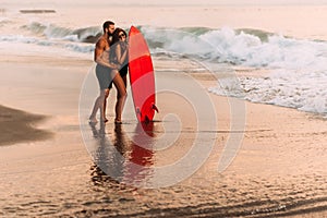 A couple in love on the beach with a surfboard. Beautiful couple on the island of Bali.