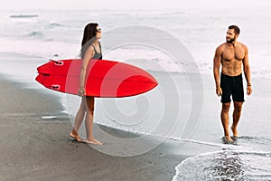 A couple in love on the beach. Surfing in Bali Indonesia. Couple of surfers walking on coast in Indonesia.