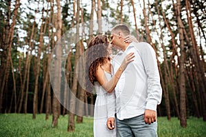 A couple in love beautiful young man and woman are kissing and hugging in a summer park on a sunny day. Date outside, well dressed