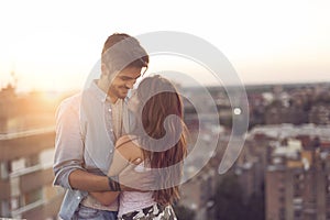 Couple in love on a building rooftop at sunset