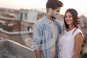 Couple in love on a building rooftop at sunset