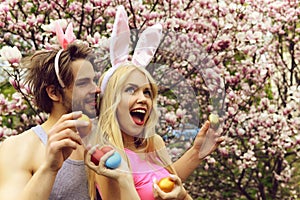 Couple in love with bunny ears holding colorful eggs