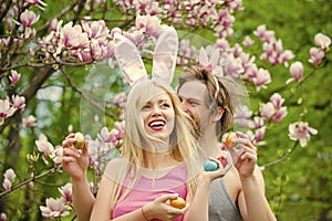 Couple in love with bunny ears holding colorful eggs