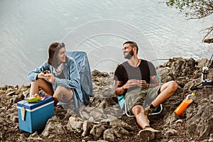 Couple in love camping forest hike. Food for hike and camping. Couple sit near bonfire eat and drink